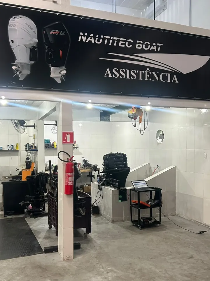 Baia de serviço com motor no cavalete e notebook no carrinho de ferramentas